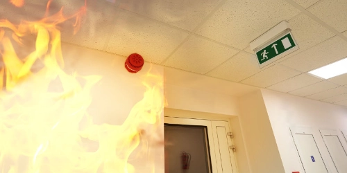 Notausgangsschild und Feuer im Flur – vorbeugender Brandschutz